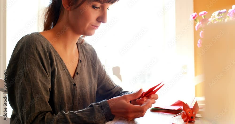Young woman preparing origami with paper at home
