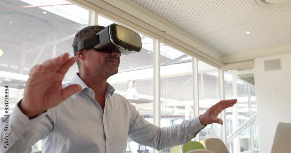 Businessman using virtual reality headset at desk in modern office 4