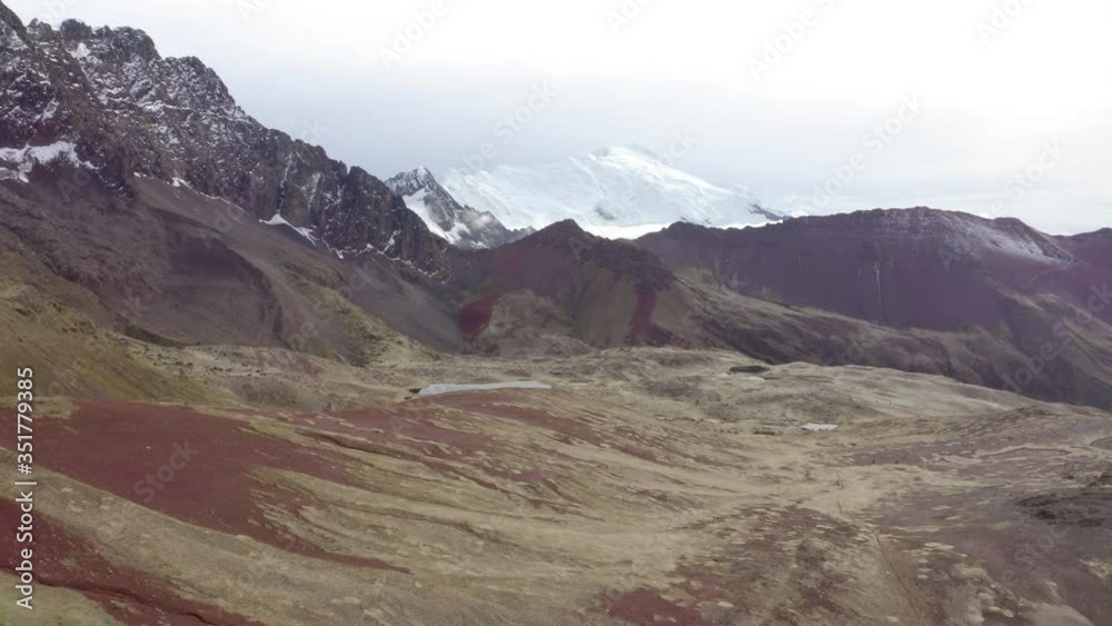 Aerial shot of idyllic rocky mountains against cloudy sky, drone moving backward from barren landscape - Rainbow Mountain, Peru Aerial shot of idyllic rocky mountains against cloudy sky, drone moving backward from barren landscape - Rainbow Mountain, Peru