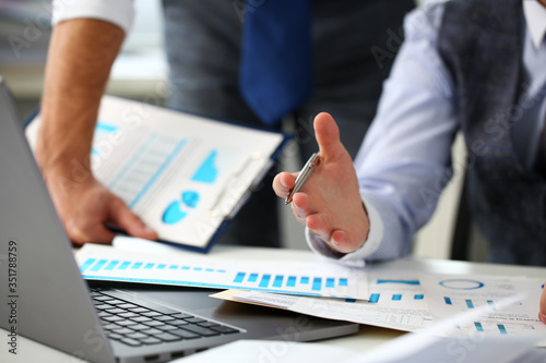 Group of businessmen point arm with silver pen at laptop pc