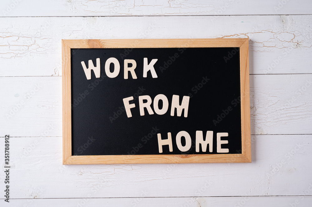 `Work from Home` words on a modern board on a white wooden surface, top view. Overhead, from above, flat lay. `Work from Home` words on a modern board on a white wooden surface, top view. Overhead, from above, flat lay.