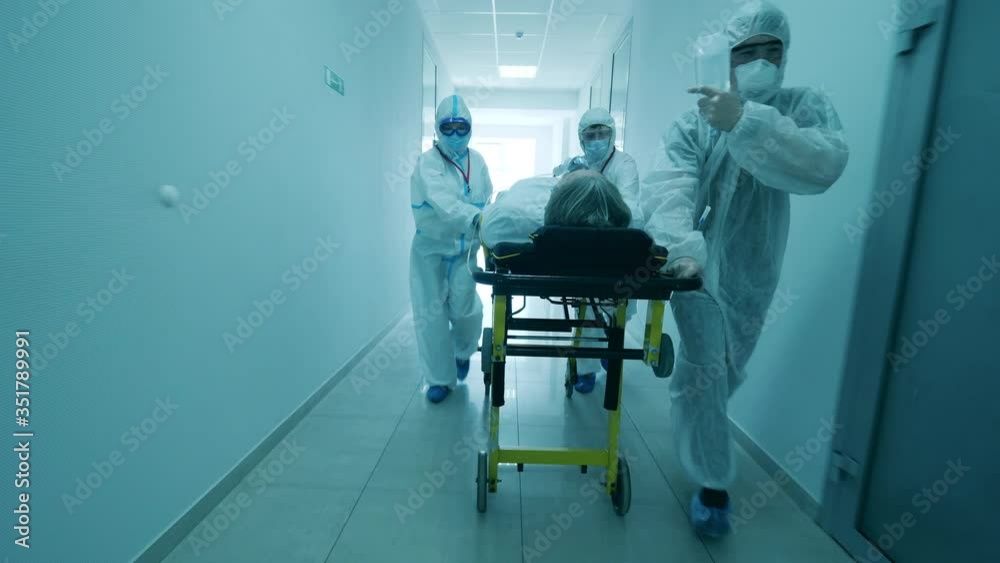 Hospital hallway with a group of doctors relocating a patient. Coronavirus hospital, COVID-19 clinic concept. Hospital hallway with a group of doctors relocating a patient. Coronavirus hospital, COVID-19 clinic concept.
