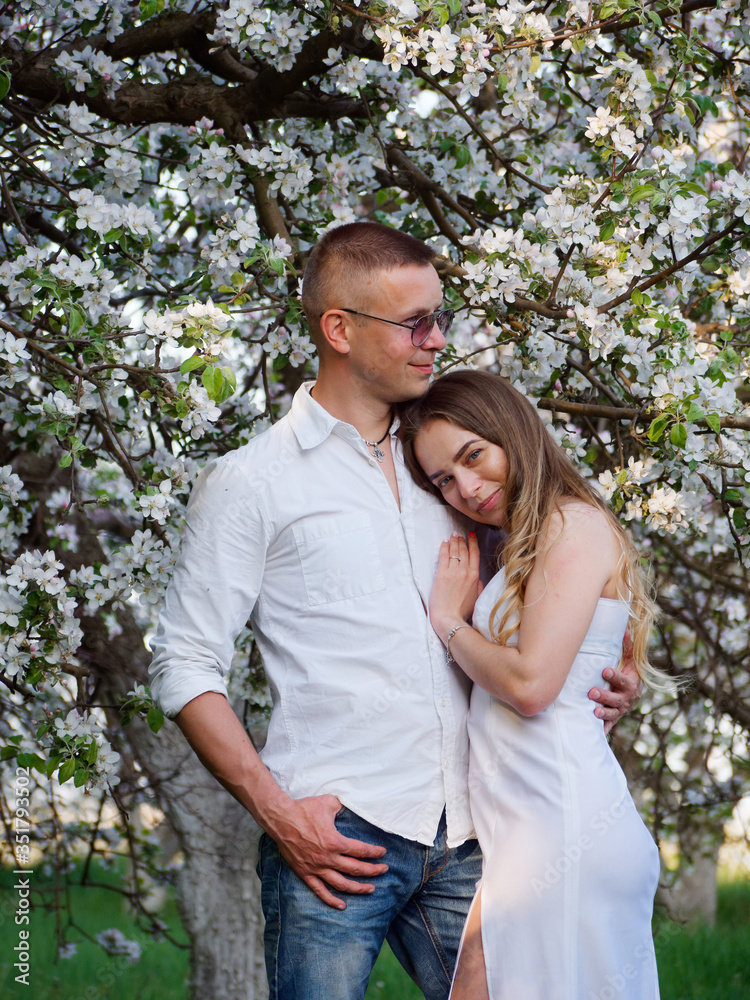 Fototapeta premium young guy and girl in blooming apple trees in the garden