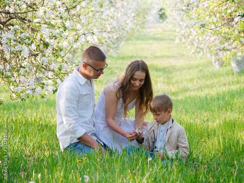 family with a child in blooming apple trees in the garden © makam1969