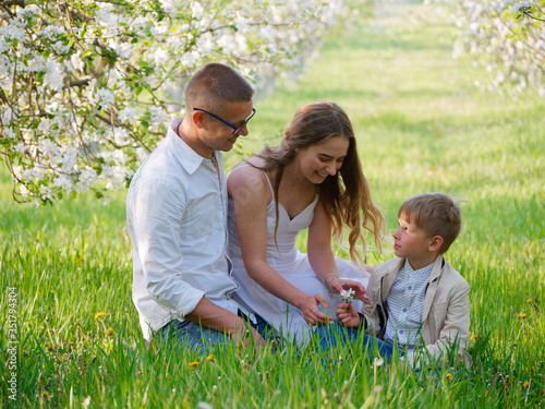 family with a child in blooming apple trees in the garden © makam1969