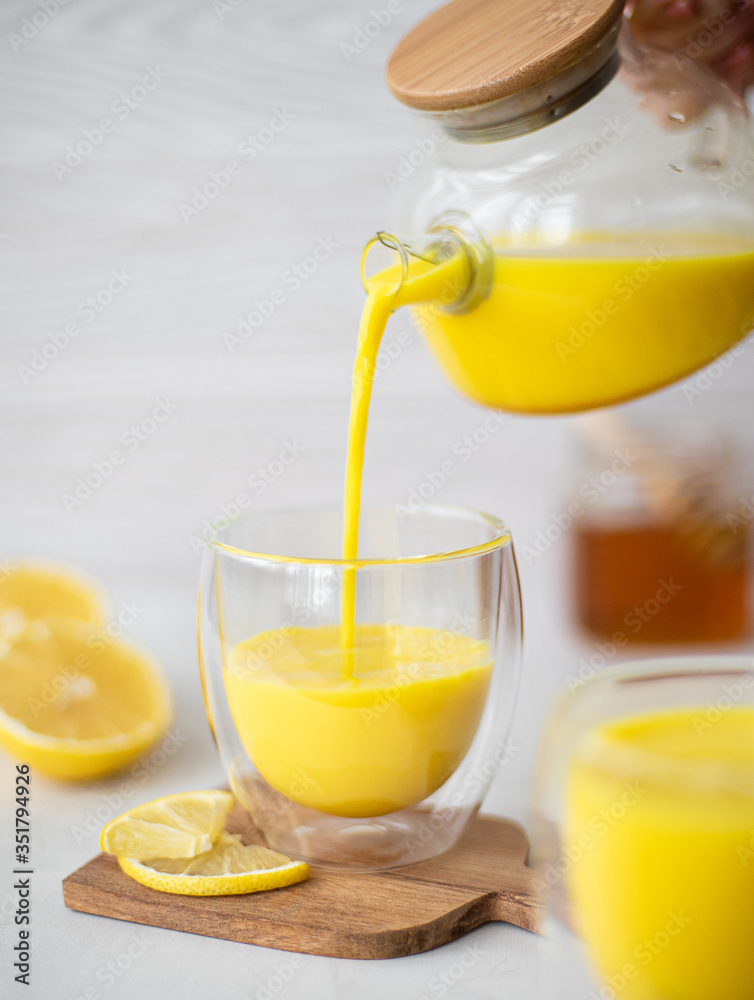 hot milk with turmeric and cinnamon in a glass bowl on a white background