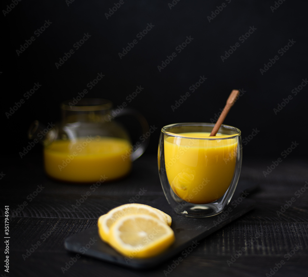 Fototapeta premium hot milk with turmeric and cinnamon in a glass bowl on a black background