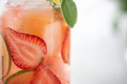 summer cocktail with lime and strawberries and a sprig of sage
