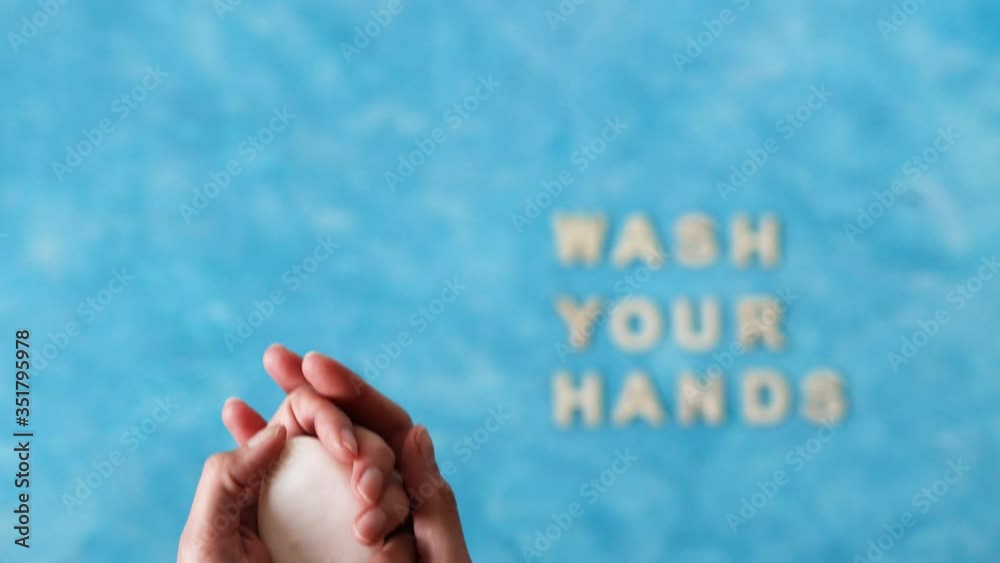hand holding soap next to Wash your Hands text with hands moving out of the frame slowly and focus switching to the text. hand holding soap next to Wash your Hands text with hands moving out of the frame slowly and focus switching to the text.