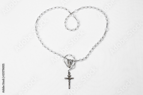 Catholic rosary with crucifix and medal of Virgin Mary on white background.
