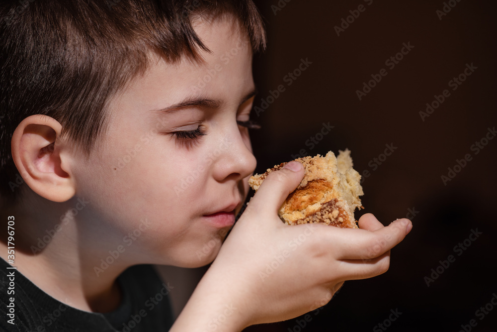 boy, child eats a bun inhales the pleasant aroma of fresh pastries. boy, child eats a bun inhales the pleasant aroma of fresh pastries.