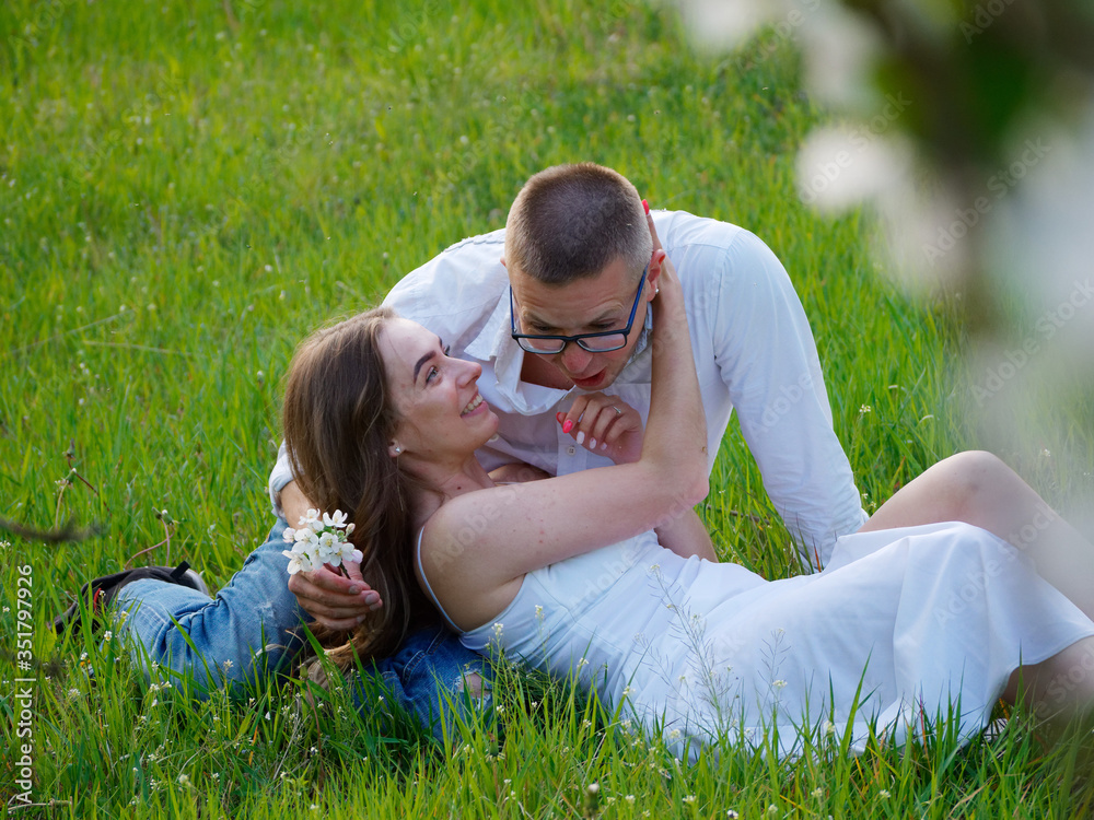 young guy and girl in blooming apple trees in the garden young guy and girl in blooming apple trees in the garden