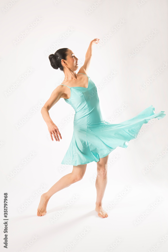Adult woman dancing in the studio in a blue dress.