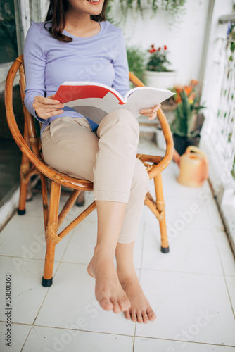 Young beautiful woman sits and reads a book on a terrace