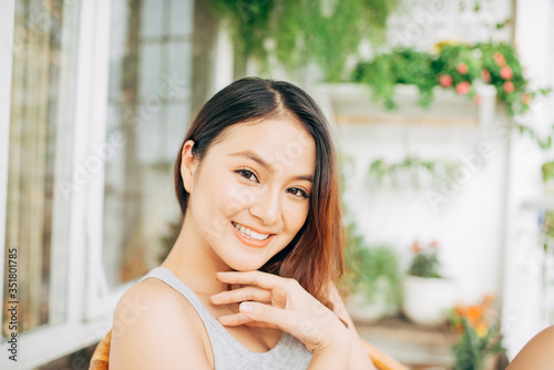 A happy asian woman sitting on a chair in balcony in the morning