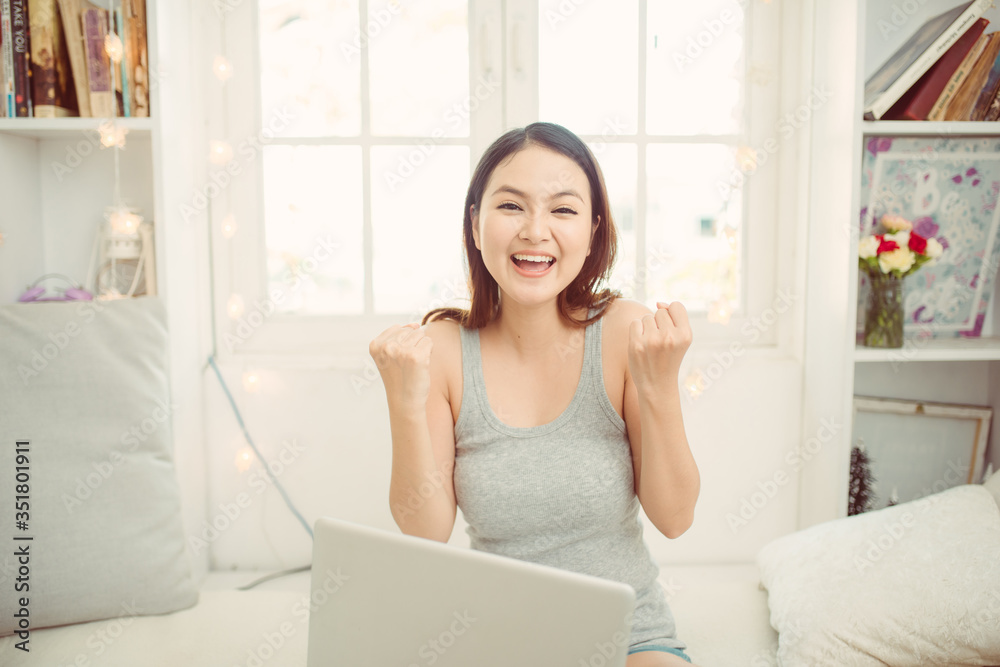 Happy asian woman using laptop while sitting on bed in the morning Happy asian woman using laptop while sitting on bed in the morning