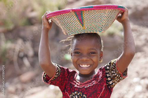 Smiling African Ethnic Girl Outdoors with Food Basket, poverty symbol photo