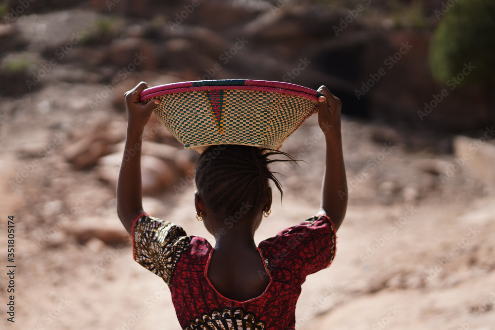 Φωτογραφία Back Photo of African Girl Transporting Basket with Food