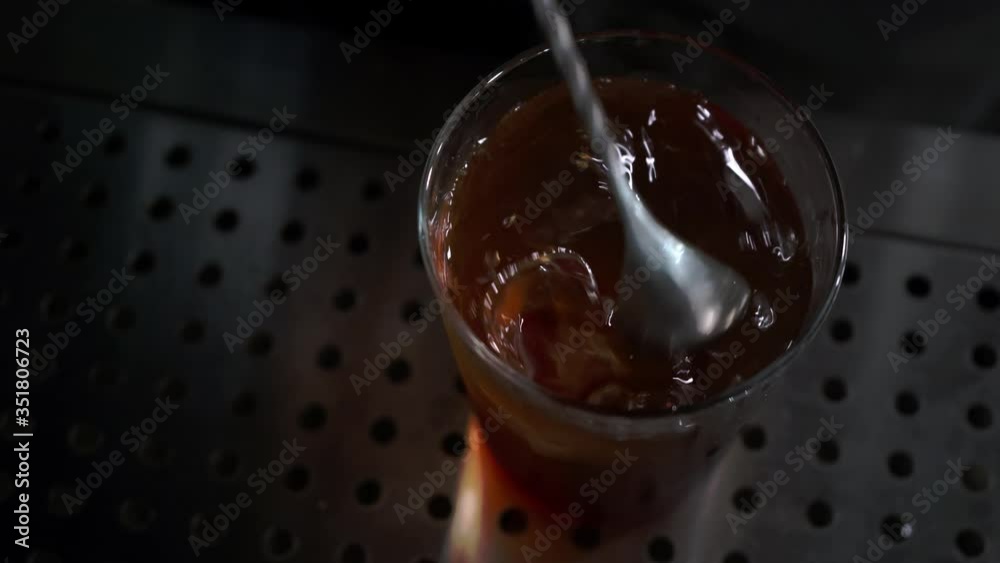 Barman stirs ingredients with a bar spoon in a glass, top view close-up Barman stirs ingredients with a bar spoon in a glass, top view close-up