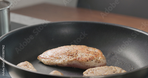 chicken fillet on non stick pan with wood spatula acloseup photo