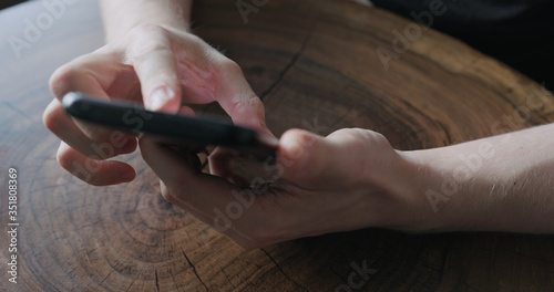 Closeup young man use smartphone while sitting at the table