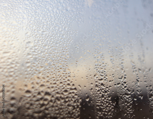 Drops of water on a glass window at dawn as an abstract background.
