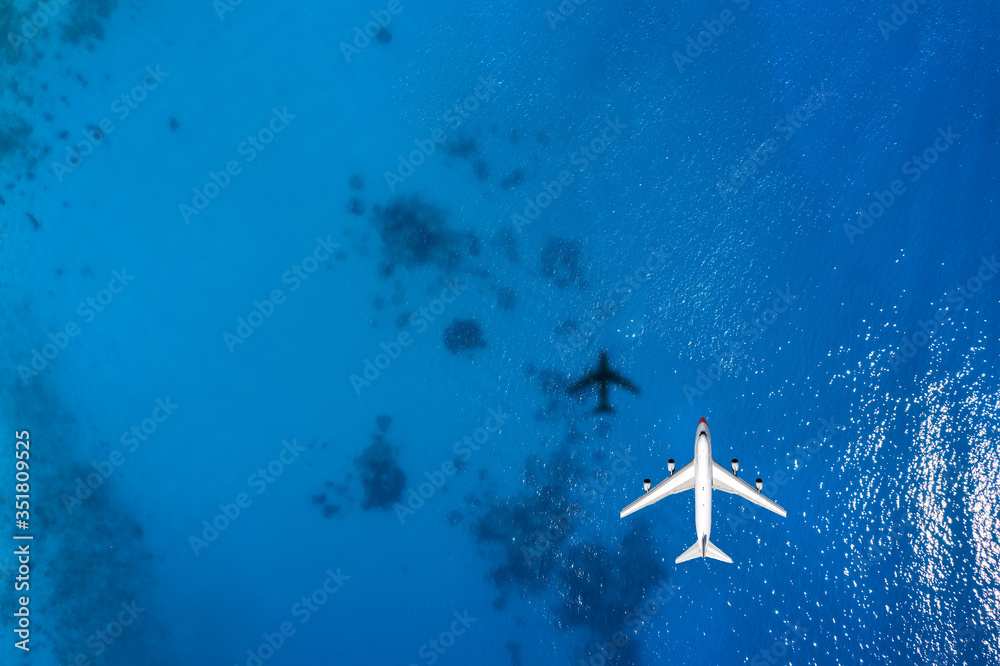 Reisekonzept mit einem Flugzeug über blauem Meer und Textfreiraum - obrazy, fototapety, plakaty 