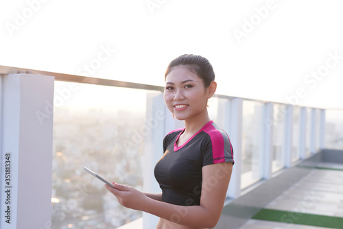 Cheerful young female fitness trainer writing on her clipboard outdoor. Free Download Cheerful young female fitness trainer writing on her clipboard outdoor. - GFXLoad
