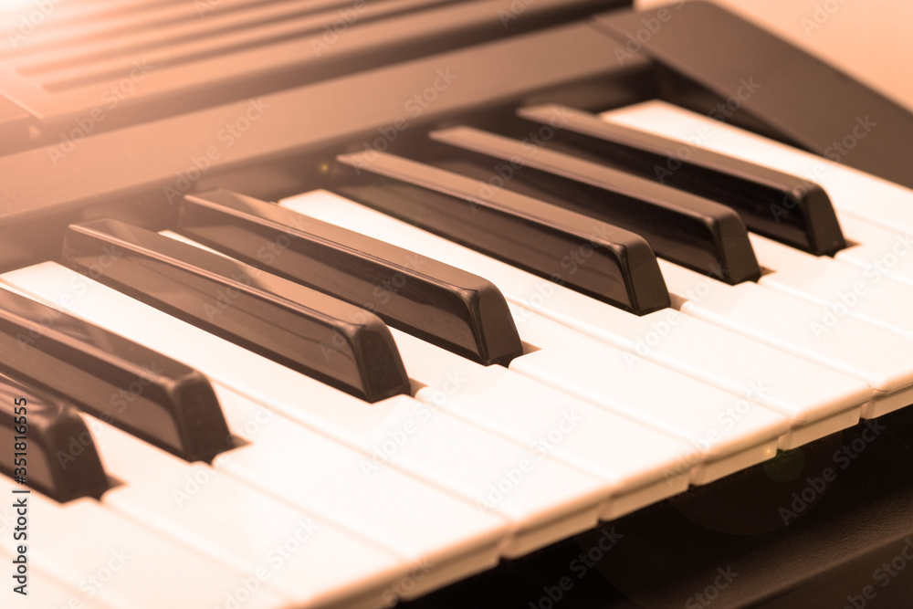 Music keyboard synthesizer, piano isolated, side view with orange backlight. Music keyboard synthesizer, piano isolated, side view with orange backlight.