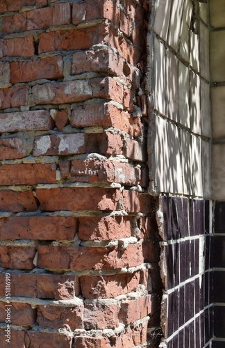 old brick wall with falling tiles in the sun
