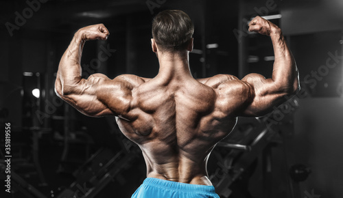 Bodybuilder strong man pumping up biceps muscles