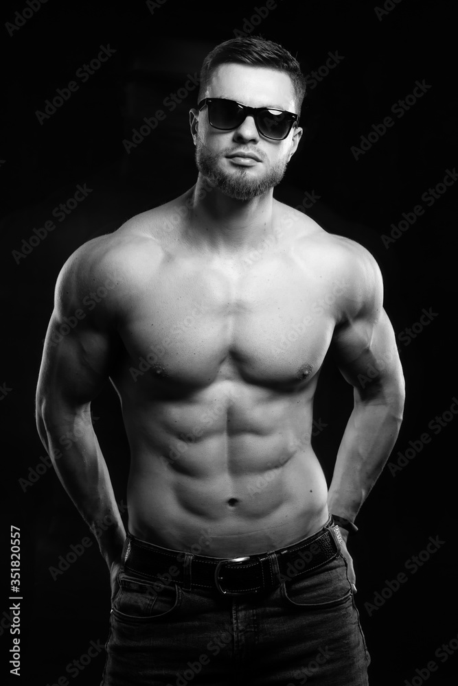 Muscular and sexy man. Naked torso of young man with perfect abs. Black and white. Half turned to the camera. Closeup.