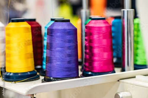 Coils with colored threads. Silk threads on bobbins. Light industry. Clothing manufacture. Sewing clothes. Weaving. The concept of sewing. Sewing background