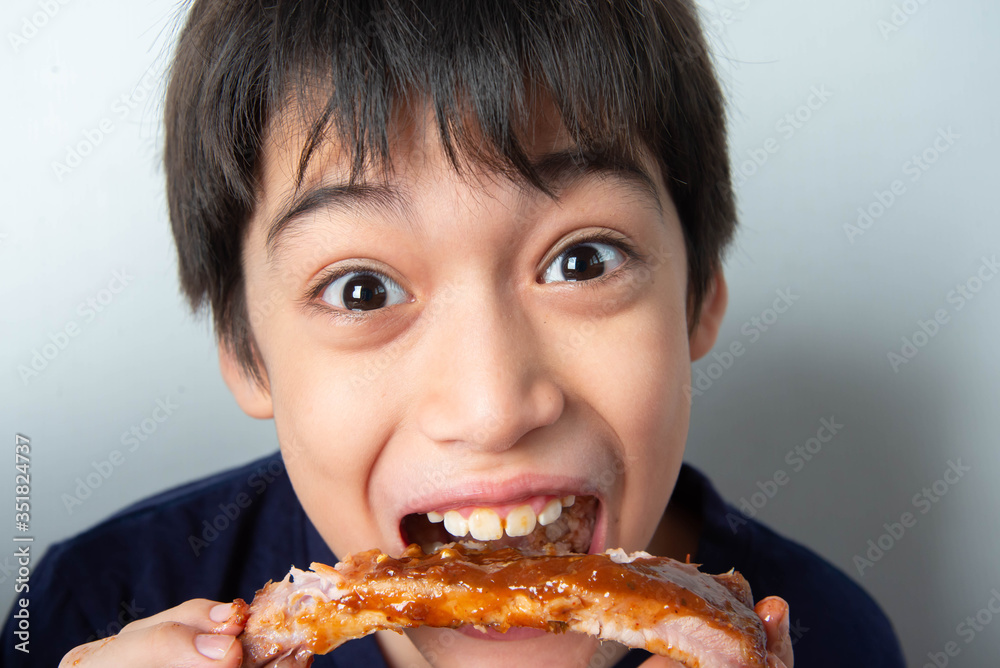 Little boy eating rib pork grill with happy face Little boy eating rib pork grill with happy face