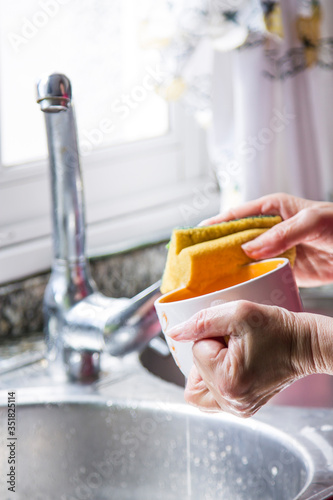 woman washing cup of coffee with scouring pad