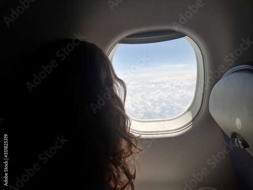 silhouette of long haired girl looking out of plane window at a desert landscape