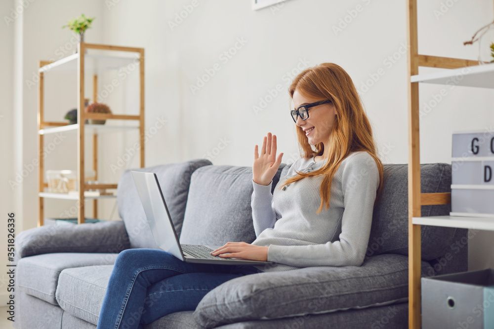 Cheerful woman making video call on sofa in room.