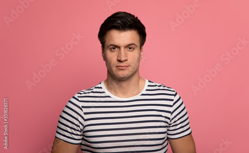 Close-up photo of a handsome serious young man who is looking in the camera confidently.