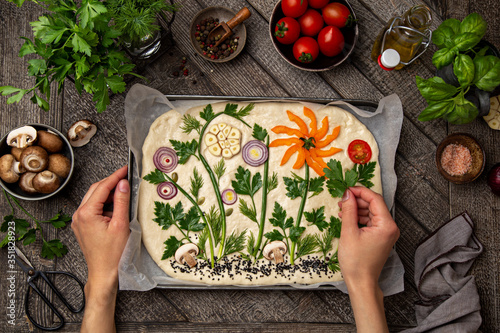 Foto female hands decorating raw floral painting focaccia,  garden flatbread art, food trend
