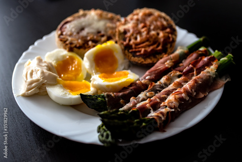 Smaczne śniadanie, szparagi, jajko, szynka parmeńska, bułki