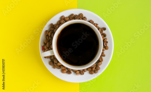 Top view, A cup of black coffee with coffee beans on yellow green background. © Andre_Dechapelle