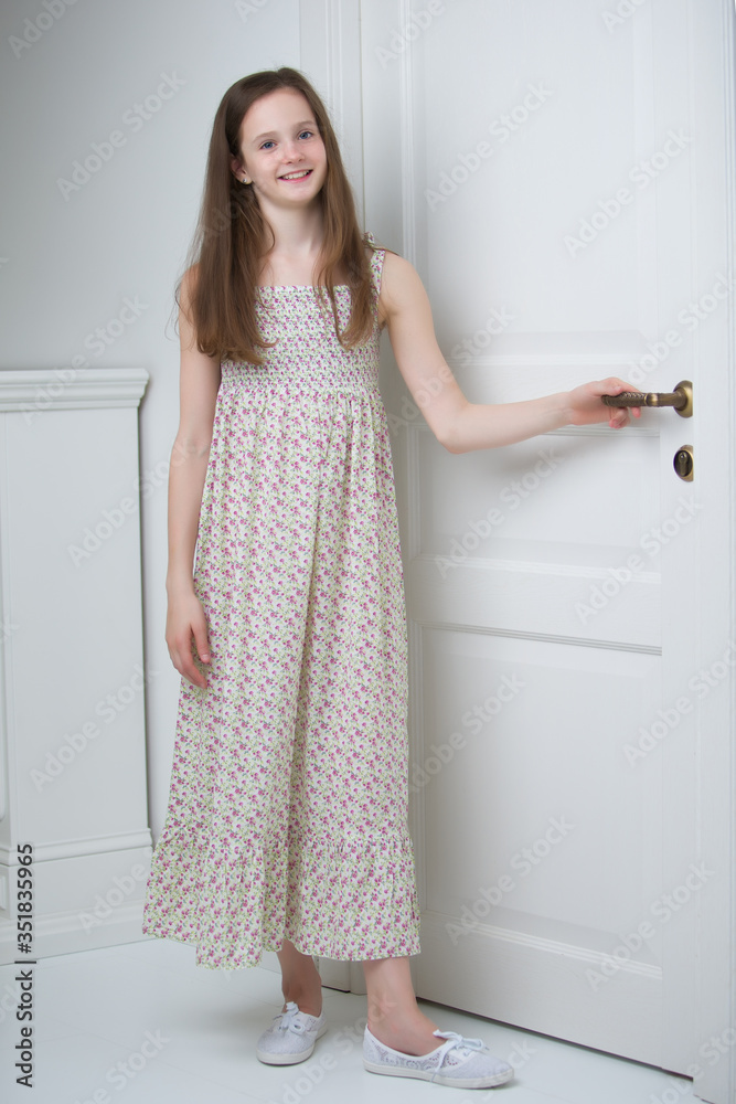 Girl teenager in a smart dress standing near the white door. Girl teenager in a smart dress standing near the white door.