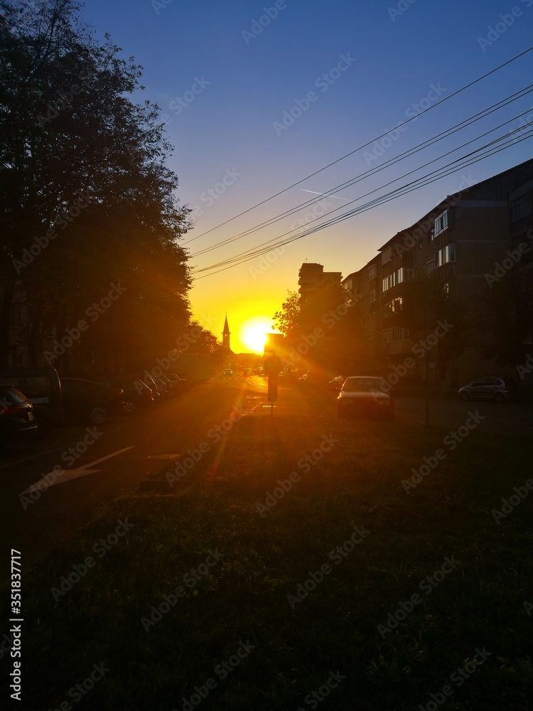 Sunshine with dazzling rays during sunset along a street between two blocks of flats