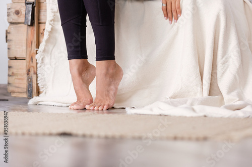 Beautiful manicured bare feet of a young unidentified woman sitting on a chair in her cozy home. Legs of a young healthy woman. Foot and Skin Health Concept. Copyspace photo