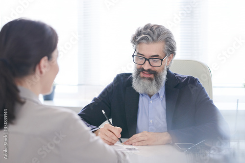 Senior male employer in eyeglasses and formalwear looking through resume