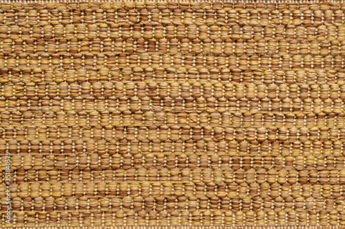 Fragment of rug, which is alternating pattern of brown and beige thick woolen threads running horizontally on basis of vertical white threads in form of short columns. Textile abstract warm background photo