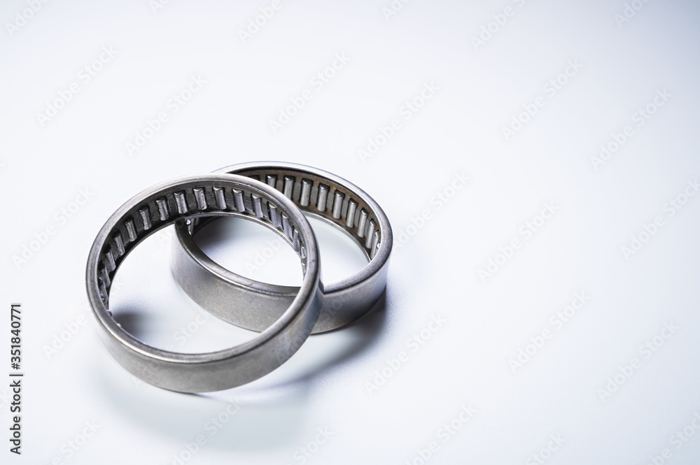 A pair of needle-bearing roller bearings on a gray background. The concept of new car parts A pair of needle-bearing roller bearings on a gray background. The concept of new car parts