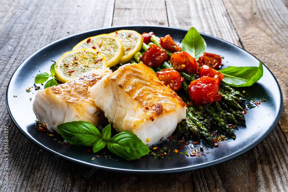 Fish dish - fried cod fillet with asparagus on wooden table
Fish dish - fried cod fillet with asparagus on wooden table