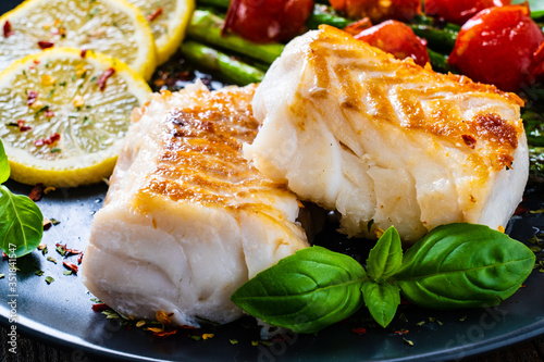 Fish dish - fried cod fillet with asparagus on wooden table
 photo