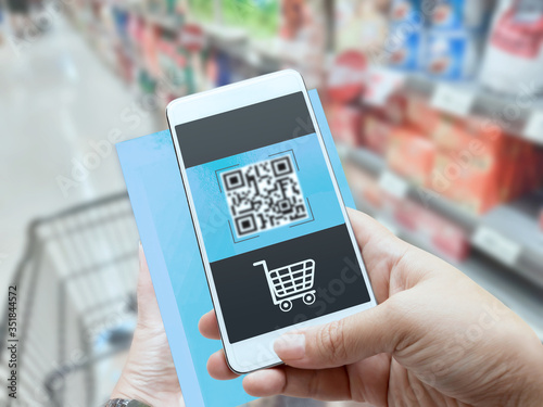 Online order grocery shopping on touch screen concept. Woman hand holding smart phone and scanning QR code for ordering ingredients food which delivery service at home for cooking.